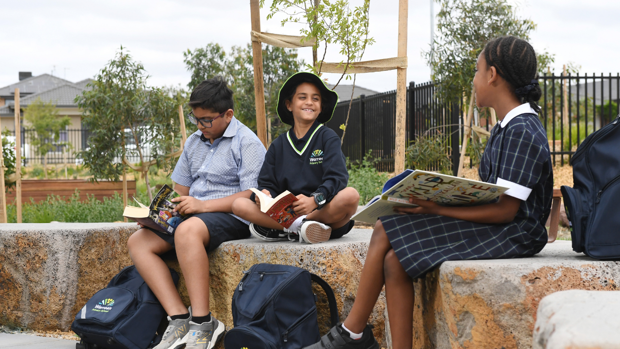 Three students sitting outside reading at school Three students sitting outside reading at school